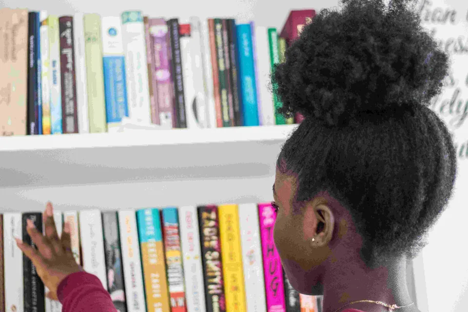 A young reader exploring books on library shelves